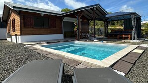 Ett modernt hus med en swimmingpool, ett trädäck och en utomhusplats med sittmöbler.
