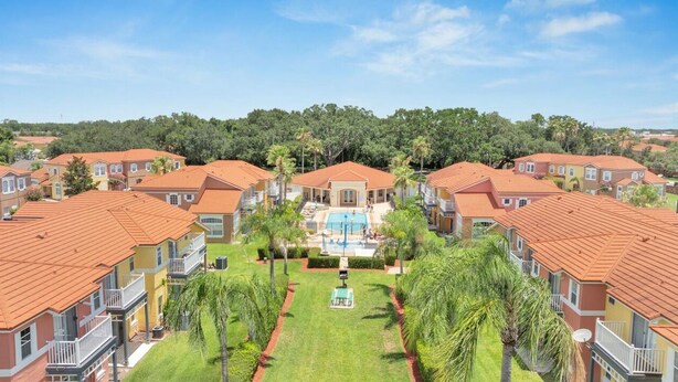Un complejo residencial con varias casas de dos pisos, una piscina central y céspedes bien cuidados.