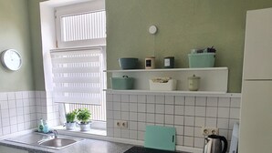 Eine Küche mit weißen Schränken, einer Spüle, einem Herd und einem Fenster mit Jalousien.