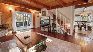 Amplia sala de estar con techo de madera, una escalera, televisor y una silla de ruedas.