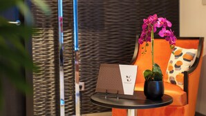 Un interior moderno con una mesa redonda, una orquídea en maceta y un sofá con un cojín estampado.