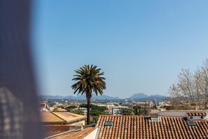 A view of a cityscape with terracotta rooftops, a prominent palm tree, and distant mountains. - Appart One Fréjus (Fréjus)