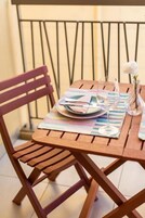Una mesa de madera con un mantel individual, un plato, un vaso y un jarrón con una sola flor.