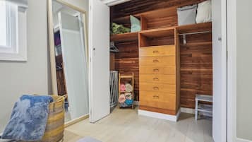 A walk-in closet with wooden shelving, a hanging rack, and a small bench.