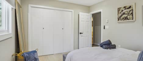 Ein Schlafzimmer mit einem Bett, einem Deckenventilator, einem großen Kleiderschrank und einem Fenster.