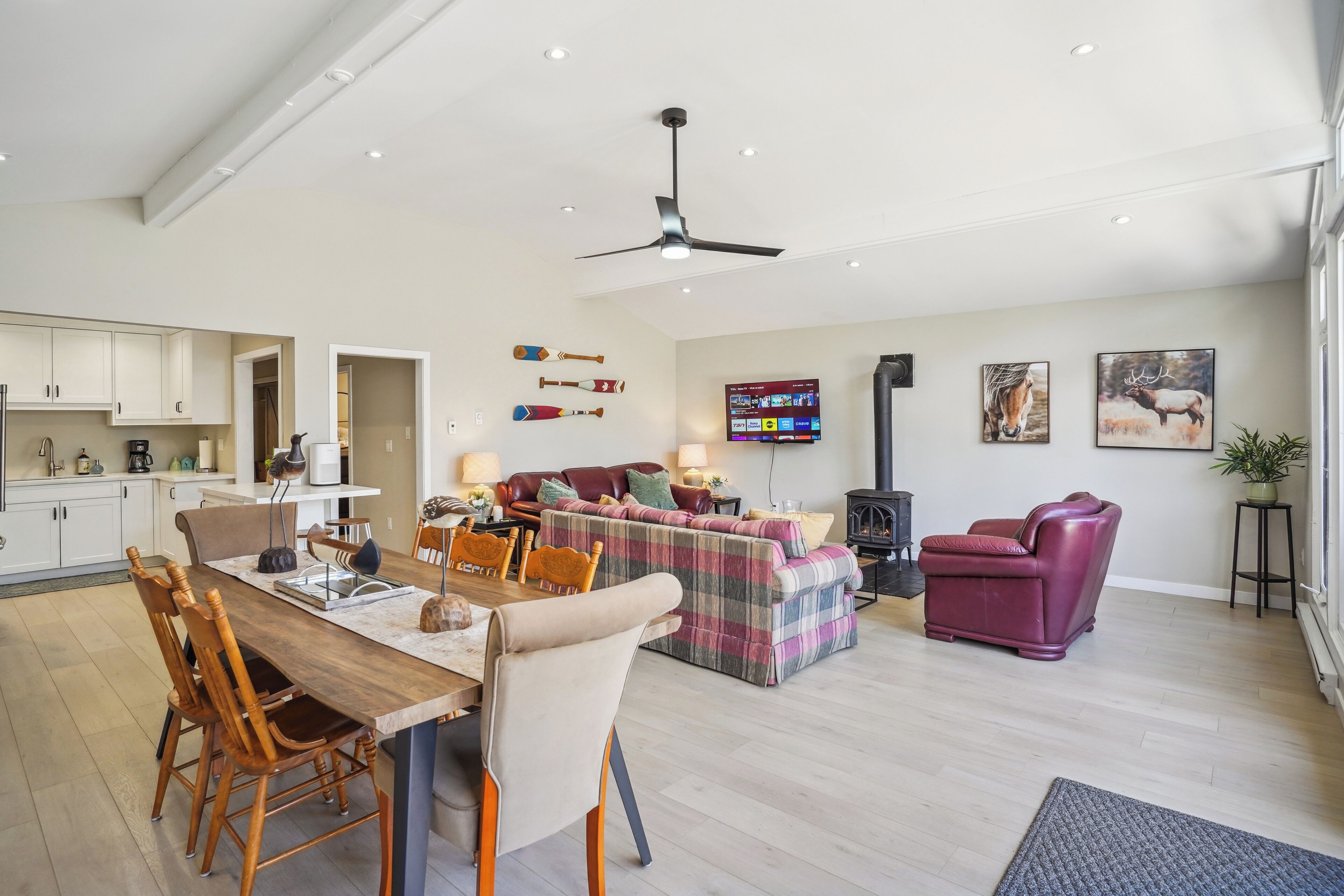 Un vaste espace de vie comprenant une table à manger, des chaises, un canapé et un fauteuil de massage.