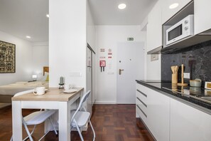 Une chambre d’hôtel compacte comprenant un coin cuisine, un espace repas avec une table et des chaises, et un lit.
