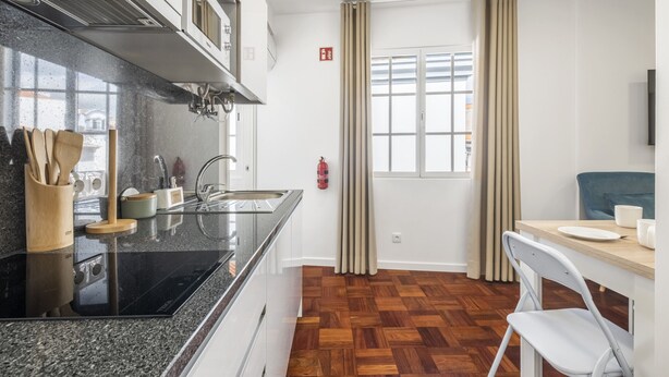 A modern kitchen with a black countertop, wooden utensils, and a fire extinguisher. - Ribeira do Esmeraldo 3B by Madeira Sun Travel (Funchal)