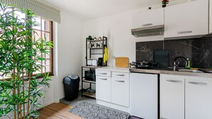 Une cuisine moderne avec des meubles blancs, un plan de travail noir et une poubelle noire.