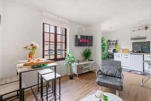 A modern living room with a dining area, a kitchen, and a TV displaying 'NETFLIX'. - Appartement de 38m2, 1 à 7 Personnes, Cdg, Jo24, Disneyland Paris 28min (Le Pin)