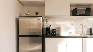A compact kitchen with a stainless steel refrigerator, a microwave, and a sink. - Venetian Breeze Cozy Studio #7 (Venetian Road Settlement)
