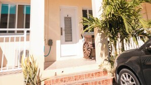 A two-story building with a balcony, a door, and a parked car. - Venetian Breeze Cozy Studio #7 (Venetian Road Settlement)