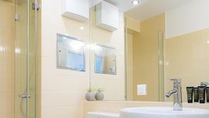 A modern bathroom with a glass-enclosed shower, a white toilet, a large sink with a mirror above, and toiletries on the countertop. - Vienna Residence, Rochusmarkt - Wien Mitte #6427 (Vienna)