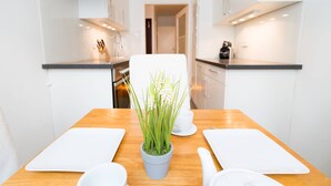 Una cocina moderna con gabinetes blancos, una mesa de comedor de madera y una planta en maceta.