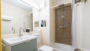 Ein modernes Badezimmer mit Waschbecken, Toilette, Badewanne und Dusche.