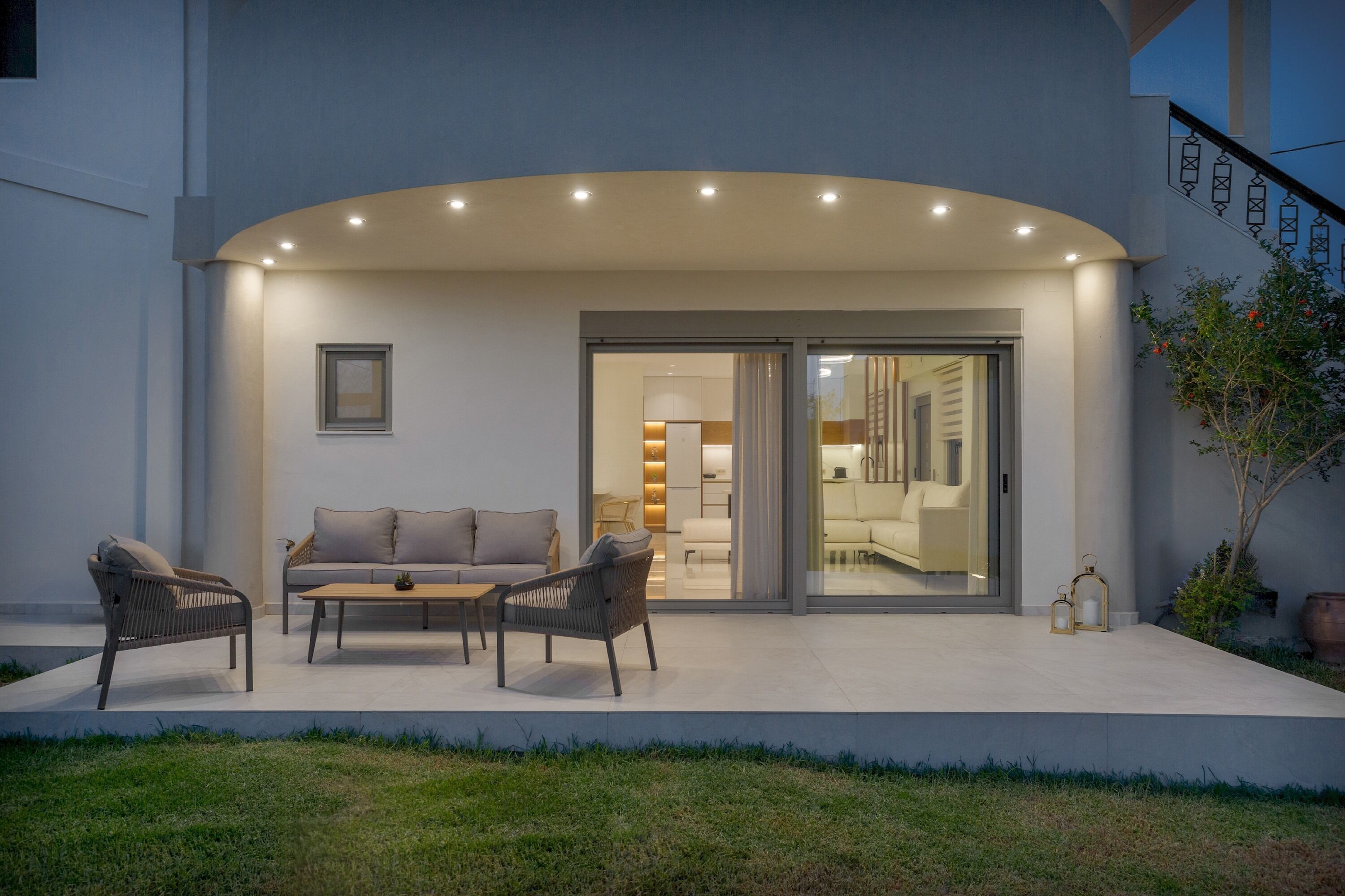 Une terrasse extérieure avec un canapé, deux fauteuils et une table basse.