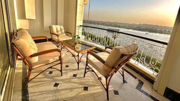 A balcony with wicker furniture and a view of a river. - Nile view appt, Cornish al Nile (Cairo)