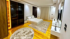 A modern bedroom with a bed, a large mirror, a wardrobe, and a round ottoman. - Nile view appt, Cornish al Nile (Cairo)