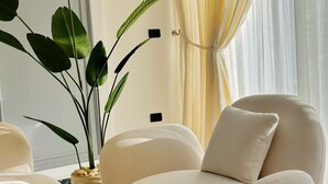 A modern living room with a plush armchair, a large potted plant, and a marble floor. - Nile view appt, Cornish al Nile (Cairo)