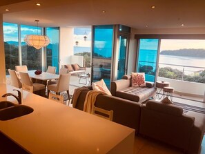A modern living room with a dining area, large windows with a view of a lake, and a balcony. - 6F Premier Corner Unit - Breathtaking Ocean Views (Panama City)