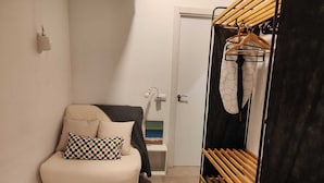 Una habitación pequeña y acogedora con una cama, un banco de madera y un perchero.