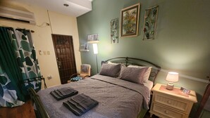 Un dormitorio con cama, mesitas de noche, lámpara y un reloj de pared.