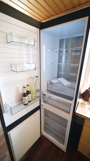 A compact refrigerator with a freezer compartment, a water dispenser, and a wine bottle holder. - Green Loft Black Forest / 120 sqm / roof balcony -- music corner (Fluorn-Winzeln)