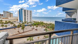 Un hotel con vista sulla spiaggia e sull'oceano, dotato di parcheggio con palme e area piscina.