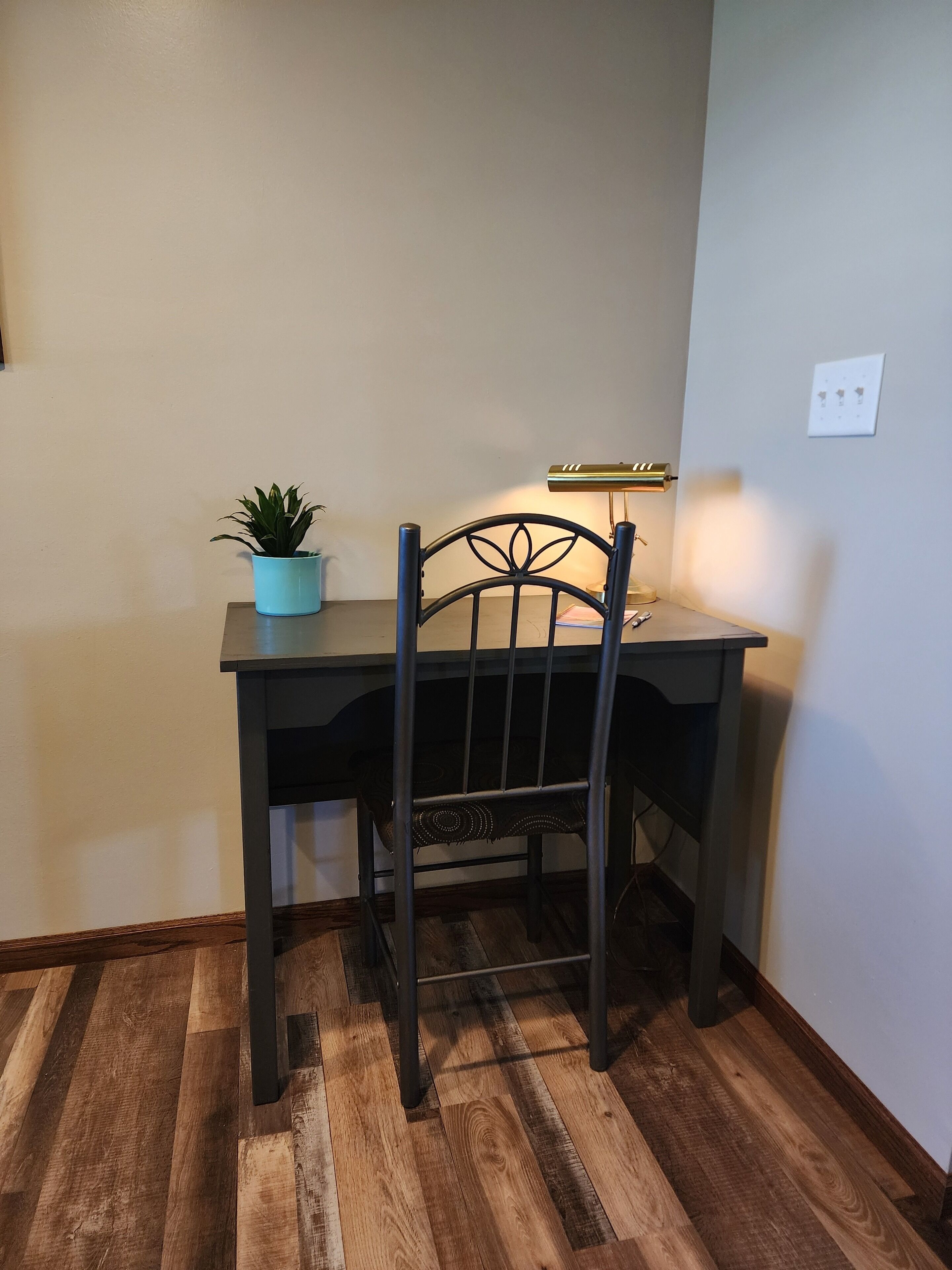 A corner desk with a metal frame, a small potted plant, and a desk lamp.