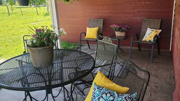 An outdoor patio with metal tables and chairs, potted plants, and a red wall.