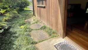 Une maison en bois avec une fenêtre, une porte et un chemin de jardin menant à l’entrée.