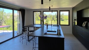 Una cocina moderna con una isla central, ventanas amplias y vistas a zonas verdes.