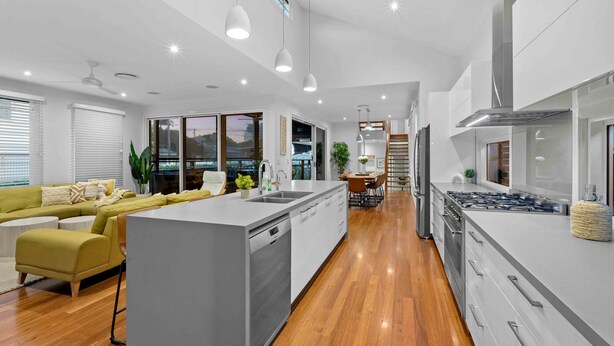 Una cocina moderna con una isla central, piso de madera y armarios blancos.
