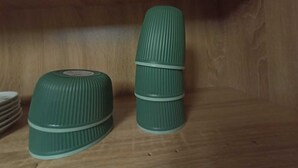 Dos contenedores verdes con textura acanalada apilados sobre un estante de madera.