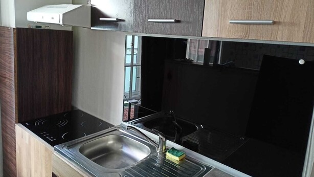 Una cocina compacta con estufa integrada, un lavamanos y armarios de madera.