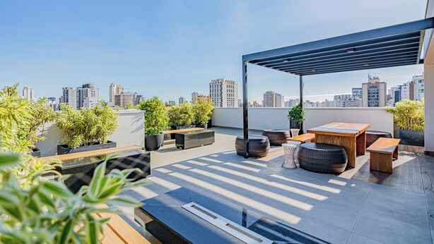 Terraza en la azotea con asientos, macetas y vistas de la ciudad.