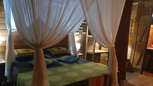 Ein Bett mit Baldachin, Kissen und einer grünen Tagesdecke.