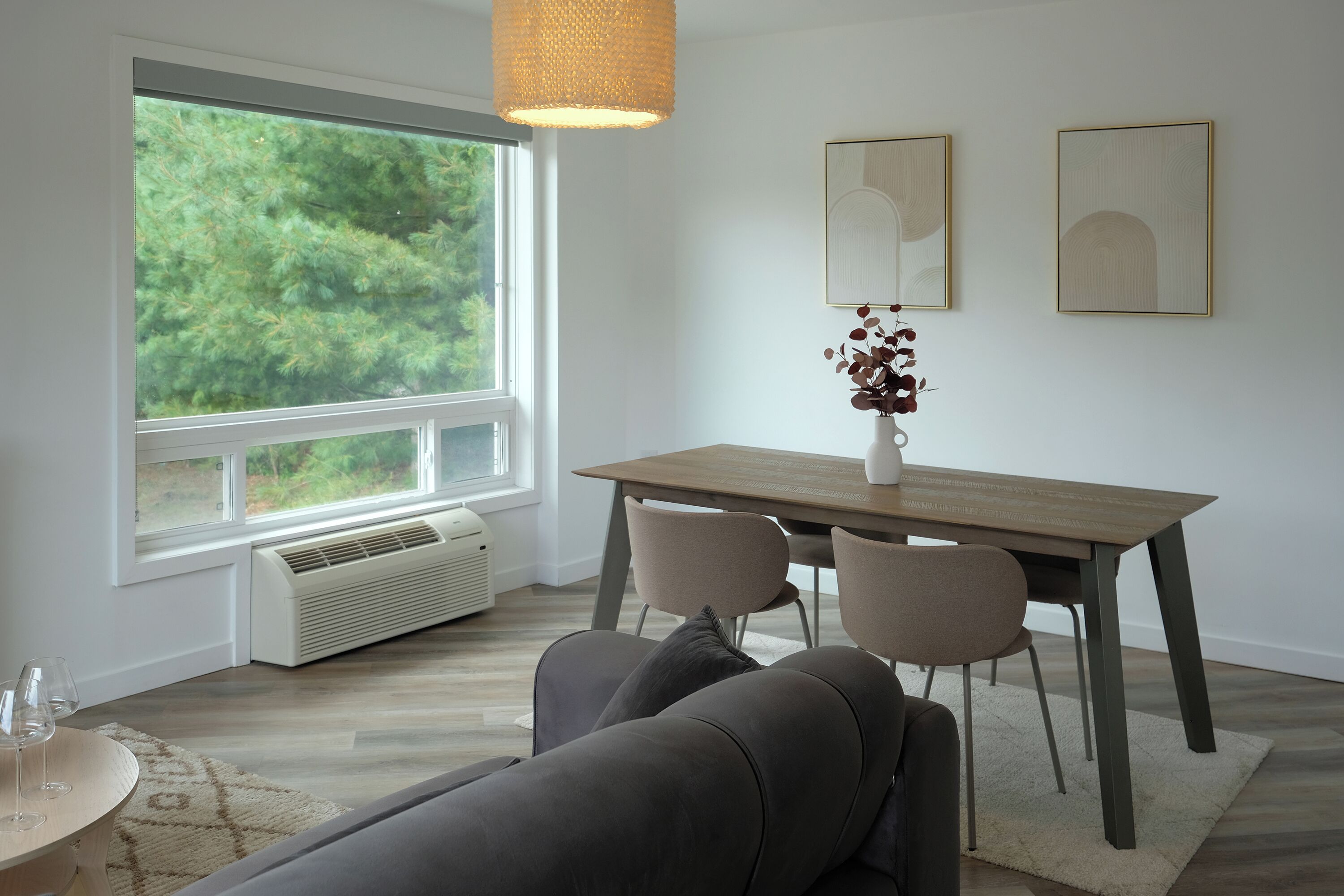 Ein modernes Wohnzimmer mit Essbereich, großen Fenstern und Blick auf Grünflächen.