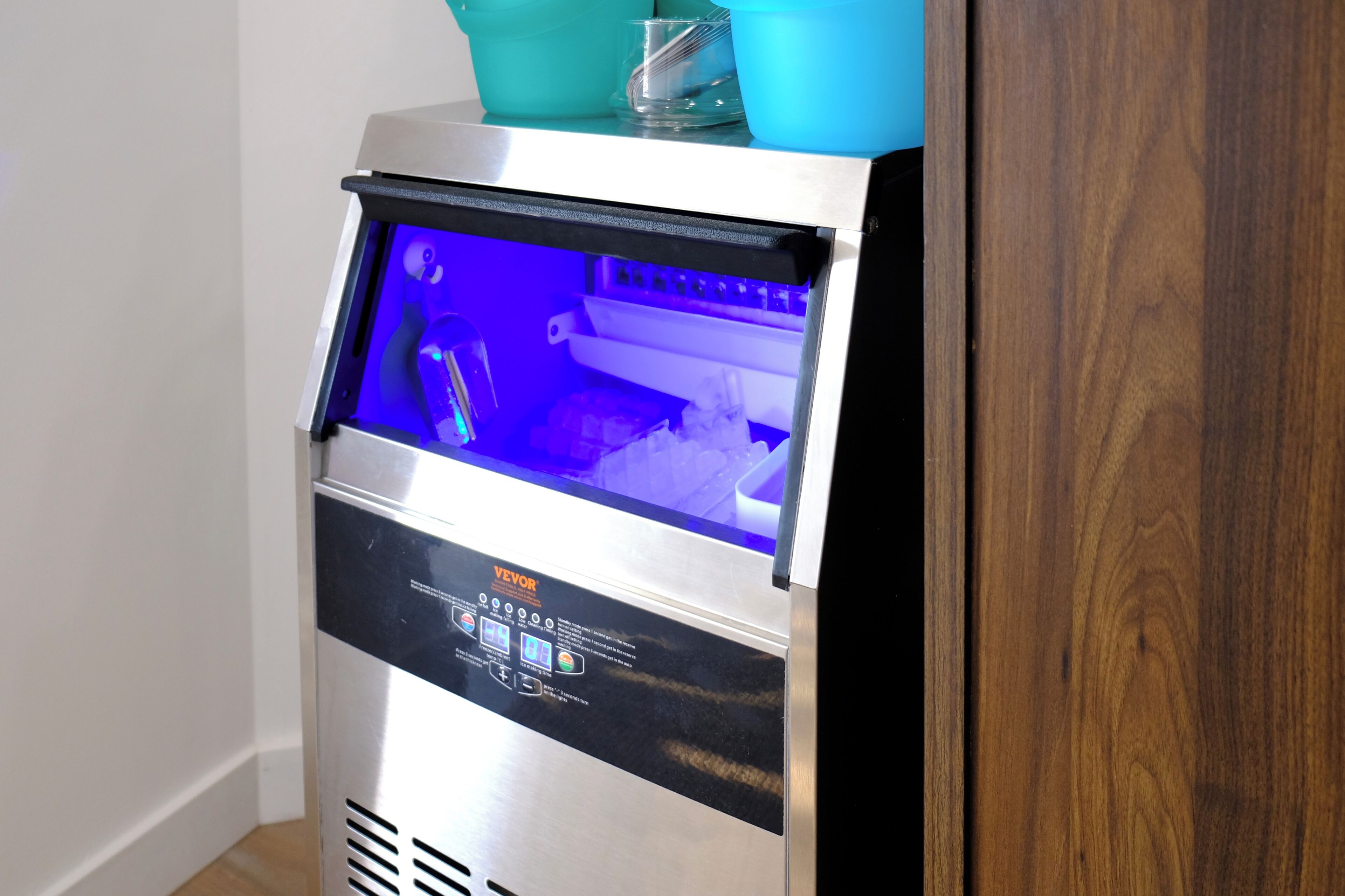 A commercial ice dispenser with a digital display and a blue light.