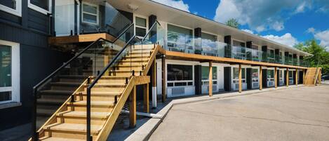 A modern building with a glass facade, wooden staircases, and a flat roof.