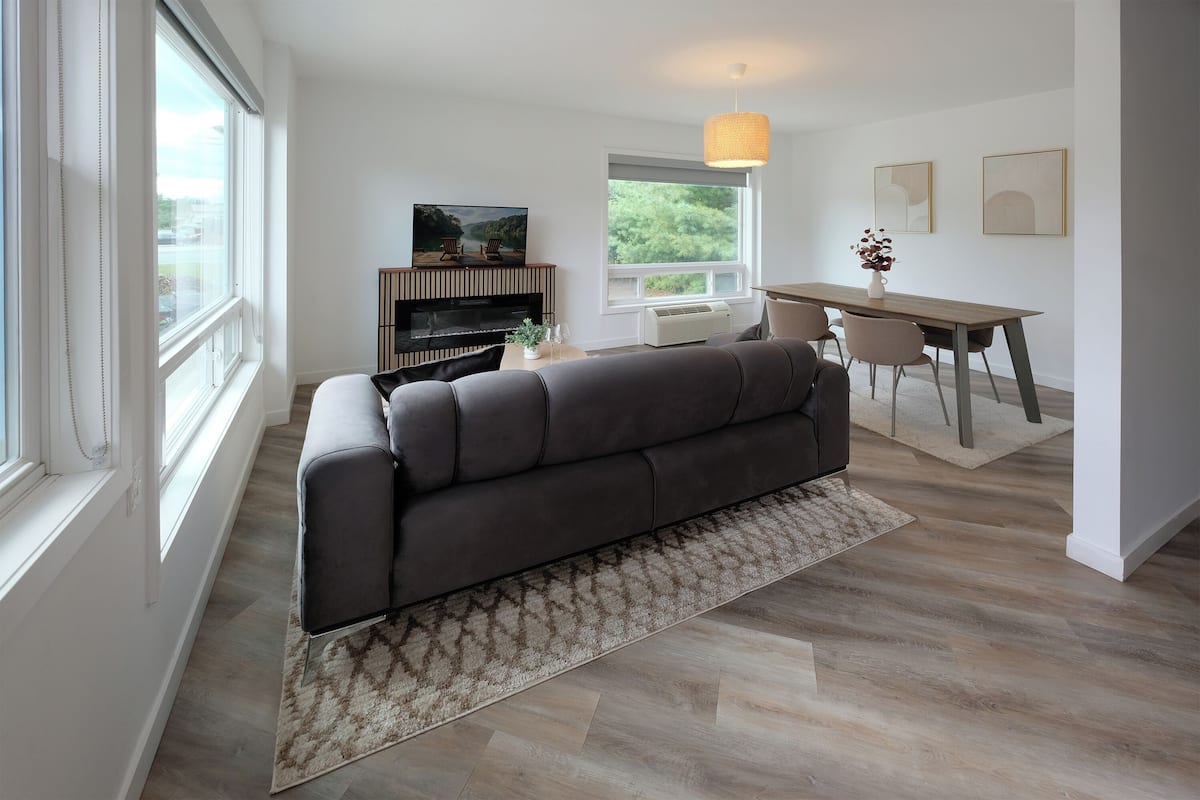 A modern living room with a sofa, a dining table, and a fireplace.