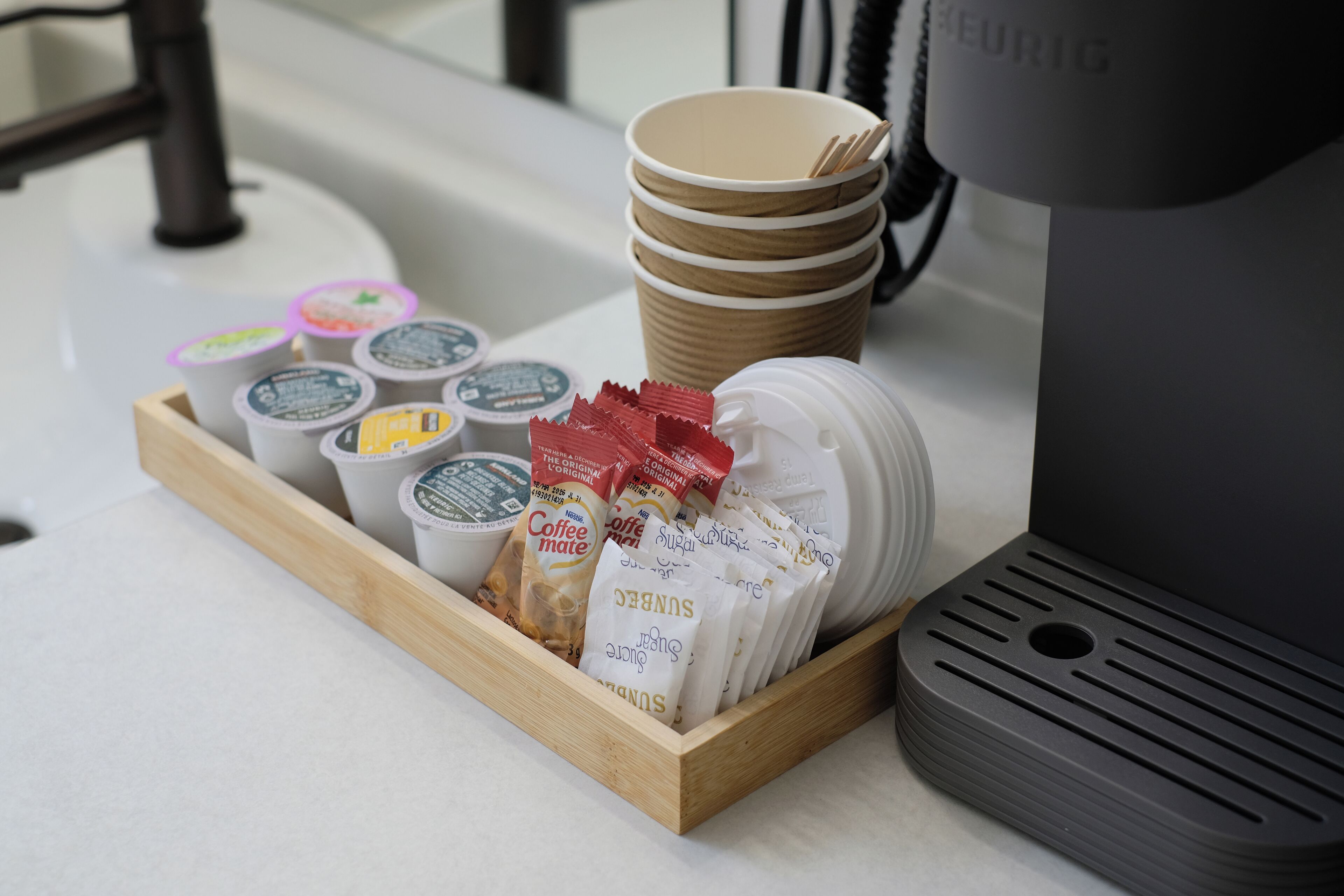 Una bandeja con cápsulas de café, bolsitas de té y una cafetera.