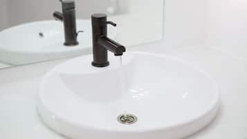 Un lavamanos blanco con un grifo moderno y un espejo encima.