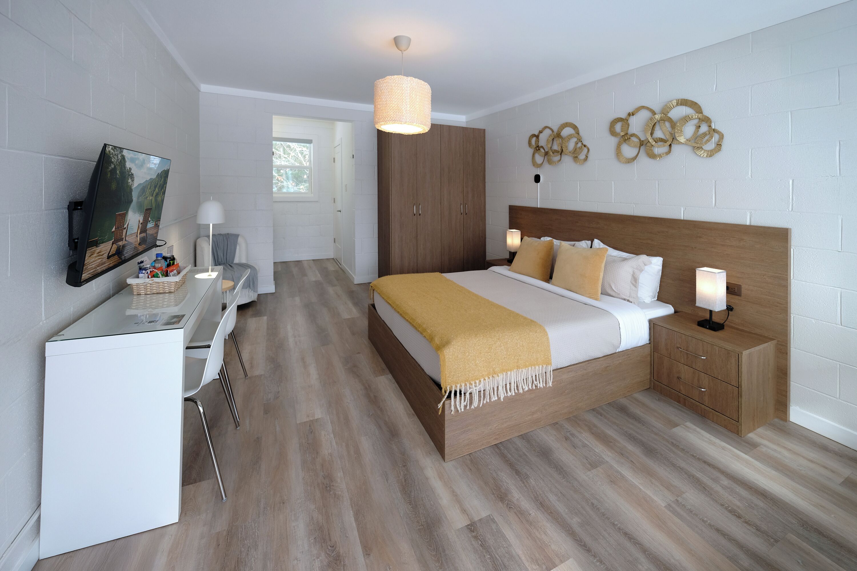 A modern bedroom with a wooden bed, bedside tables, a desk, and a TV.