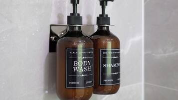 Two brown bottles of body wash and shampoo on a tiled wall.