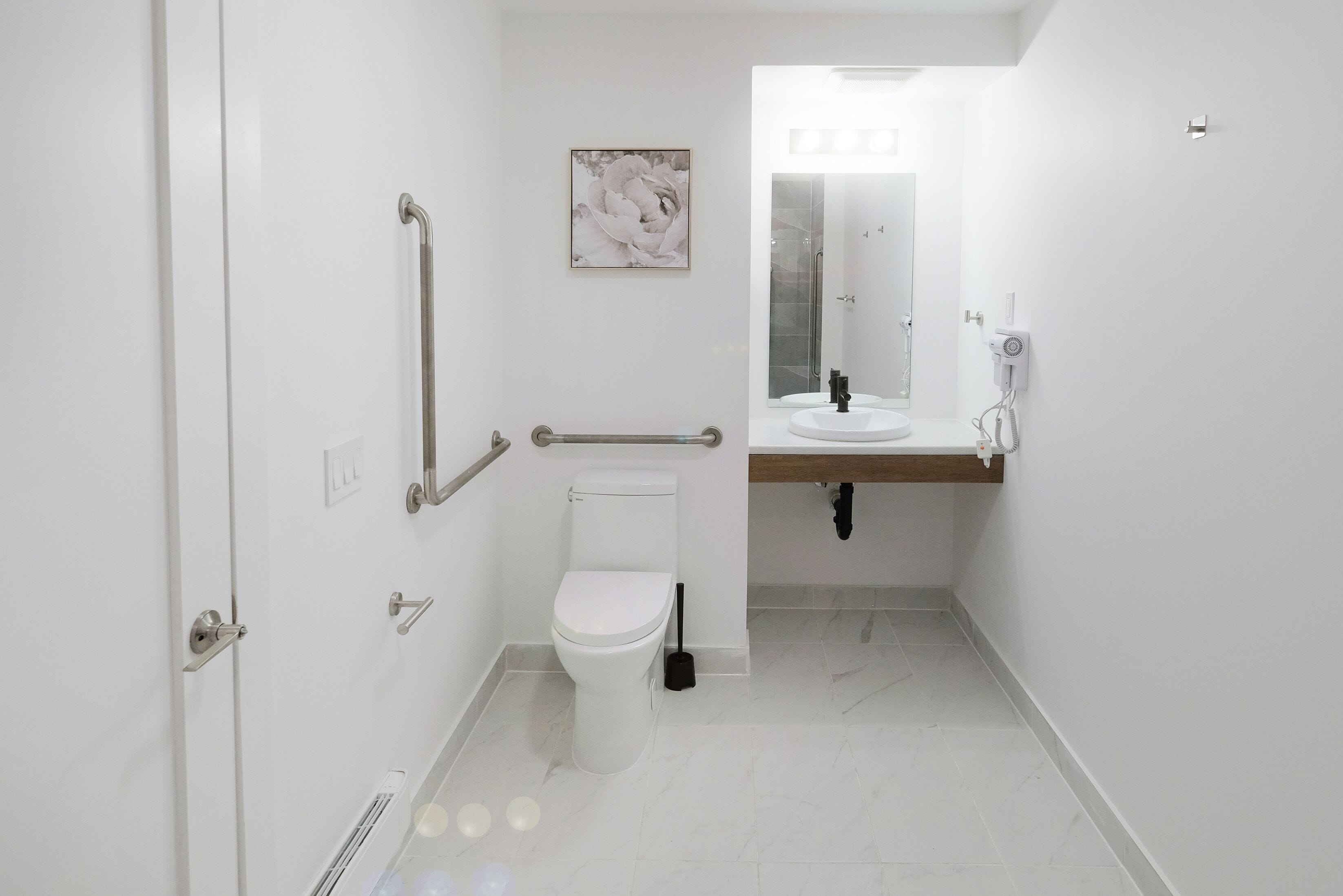 Un baño moderno con inodoro, bidé, secamanos y espejo.