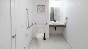 Un baño moderno con inodoro, bidé, secamanos y espejo.