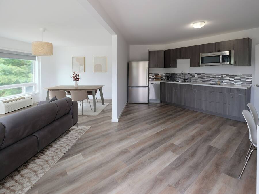 A modern kitchen with grey cabinets, stainless steel appliances, and a white countertop.