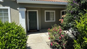 A residential house with a tiled roof, a front door, and a pathway leading to the entrance. - Cozy 4 bedroom family getaway home. Pet friendly home.  (Turlock)