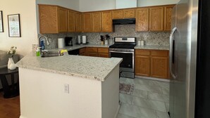 A modern kitchen with wooden cabinets, a stainless steel refrigerator, a built-in oven, and a granite countertop. - Cozy 4 bedroom family getaway home. Pet friendly home.  (Turlock)
